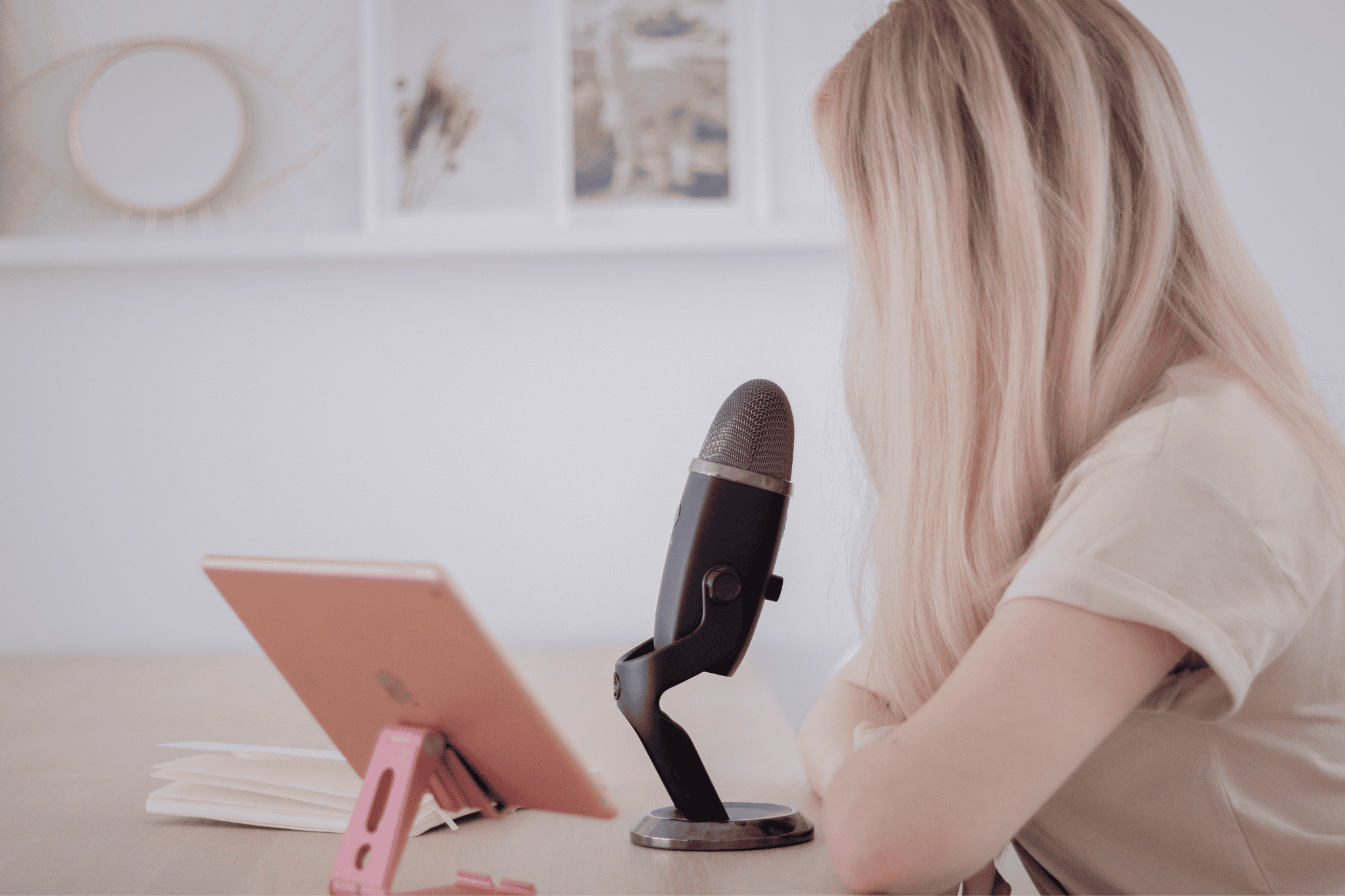 blonde woman sitting at desk with ipad and microphone