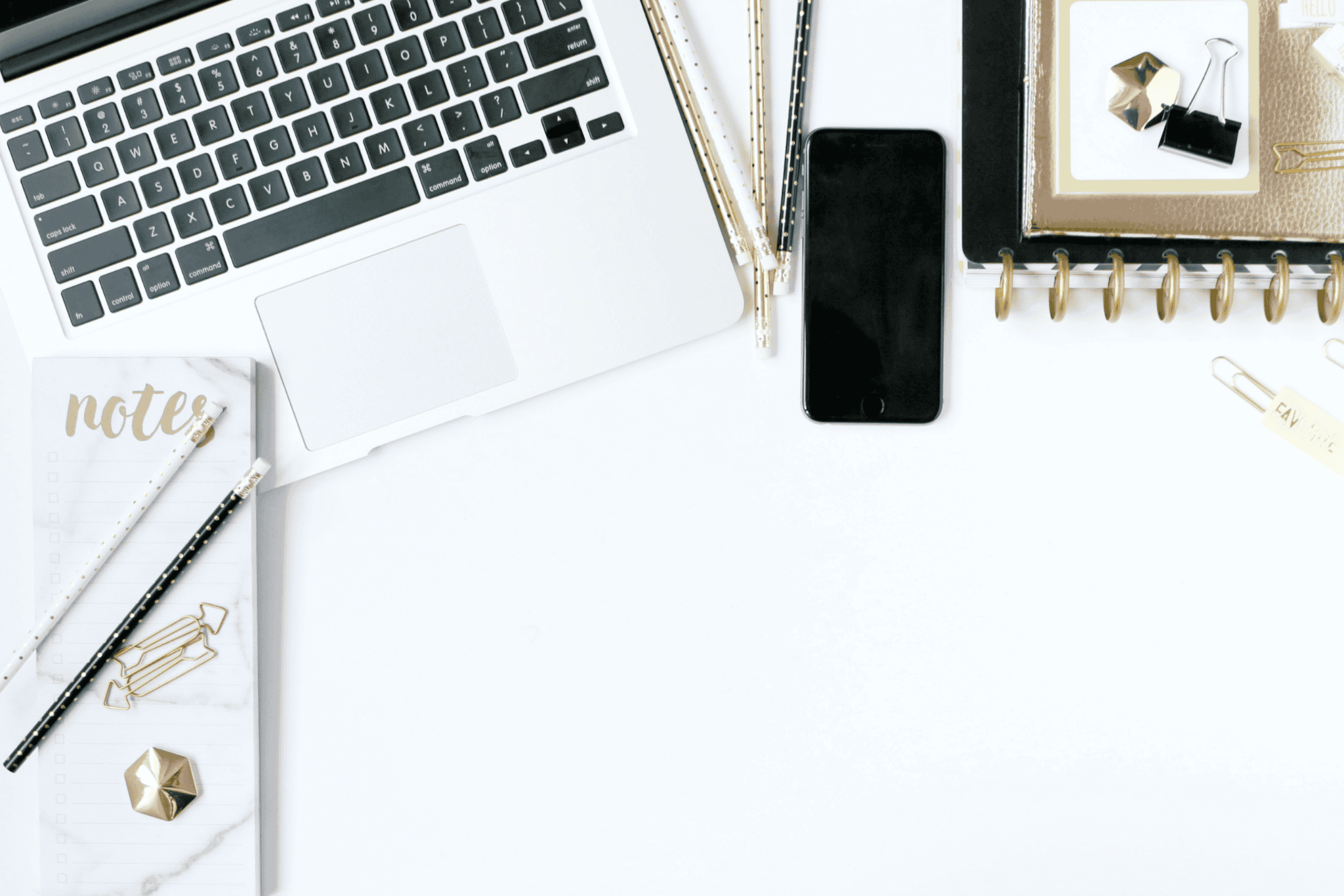 white desk with laptop, phone and notepad