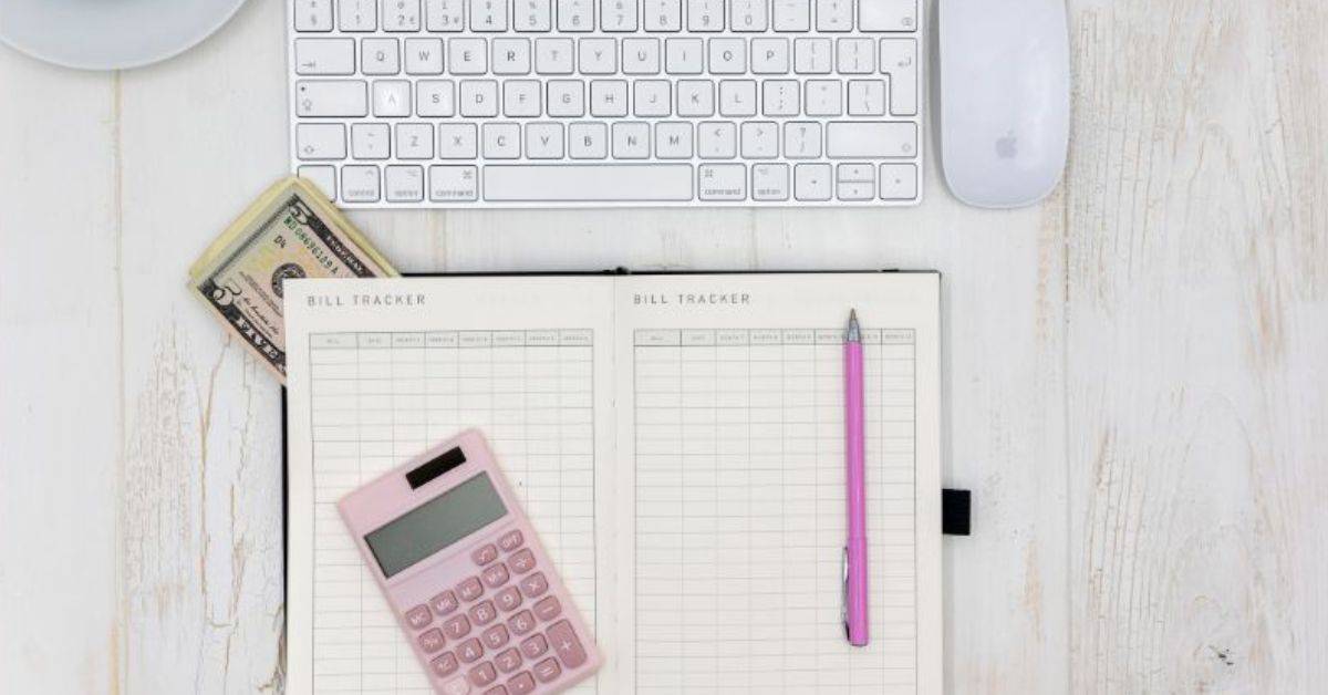 top down view of desk with budget book, pink calculator, keyboard and mouse.