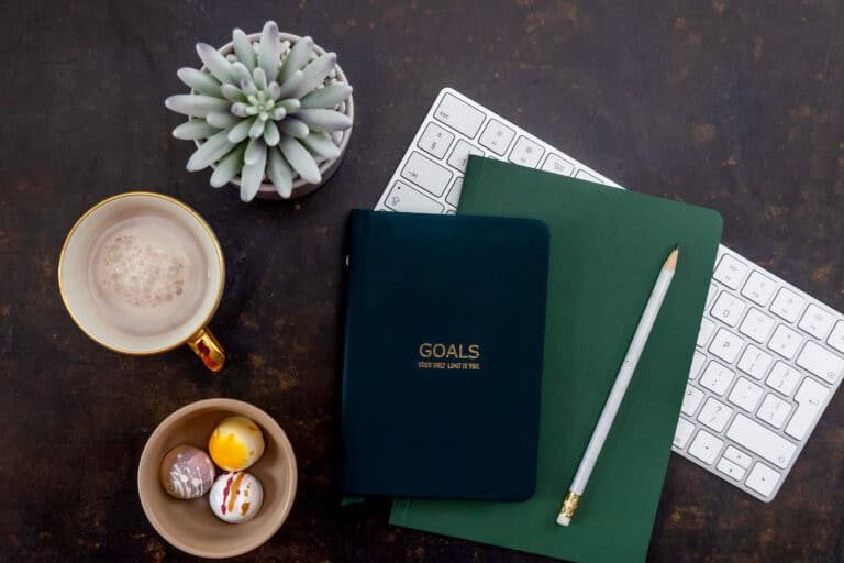 goals-notebook-pencil-colorful-chocolates-gold-mug-on-black-background